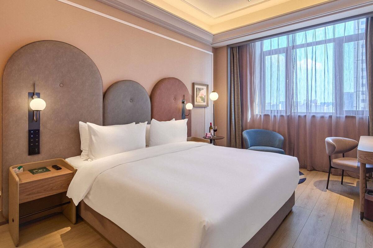 Une chambre d’hôtel avec un grand lit, des tables de chevet, un bureau et une chaise.