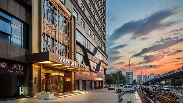 Un hôtel moderne, doté d’une entrée imposante, d’une enseigne bien visible indiquant « Mercure », et dont l’arrière-plan est constitué d’une vue sur la ville.