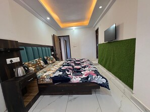 A modern bedroom with a bed, a TV, and a green wall.