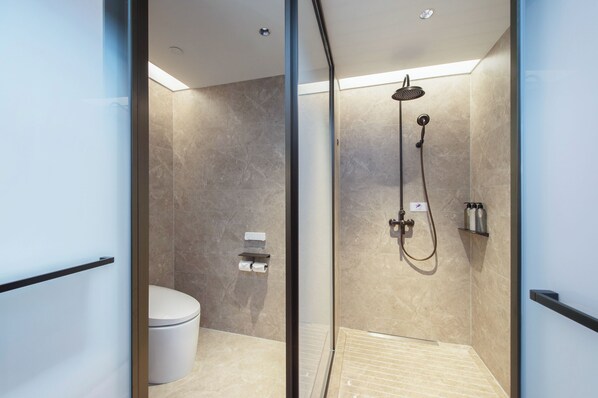 A modern bathroom with a glass partition, a toilet, a shower with a handheld showerhead, and a towel rack. - Mercure Xiamen Science City (Xiamen)