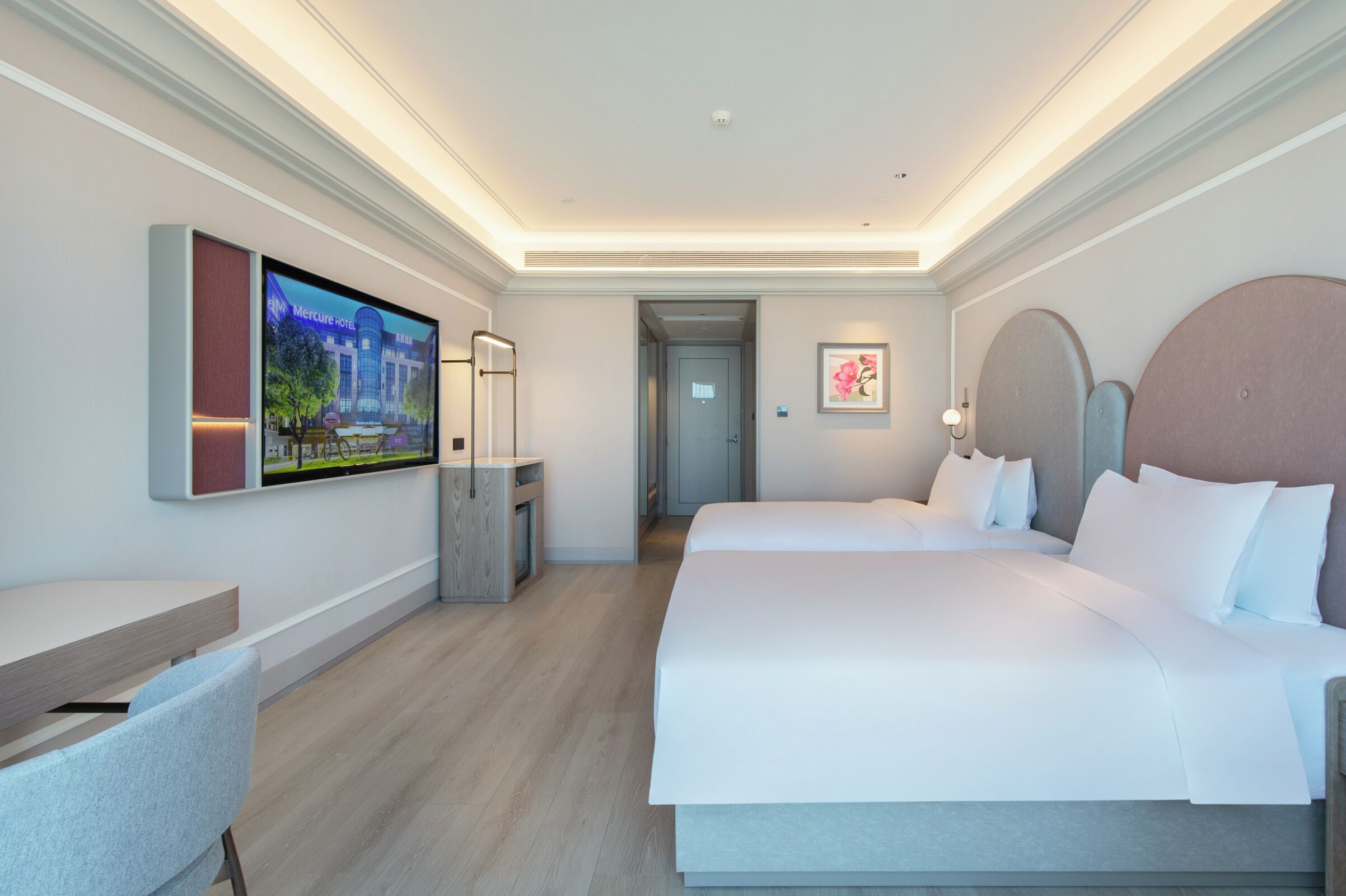A hotel room with a large bed, a desk, a TV, and a framed picture on the wall.