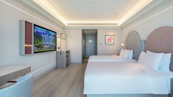 A hotel room with a large bed, a desk, a TV, and a framed picture on the wall.
