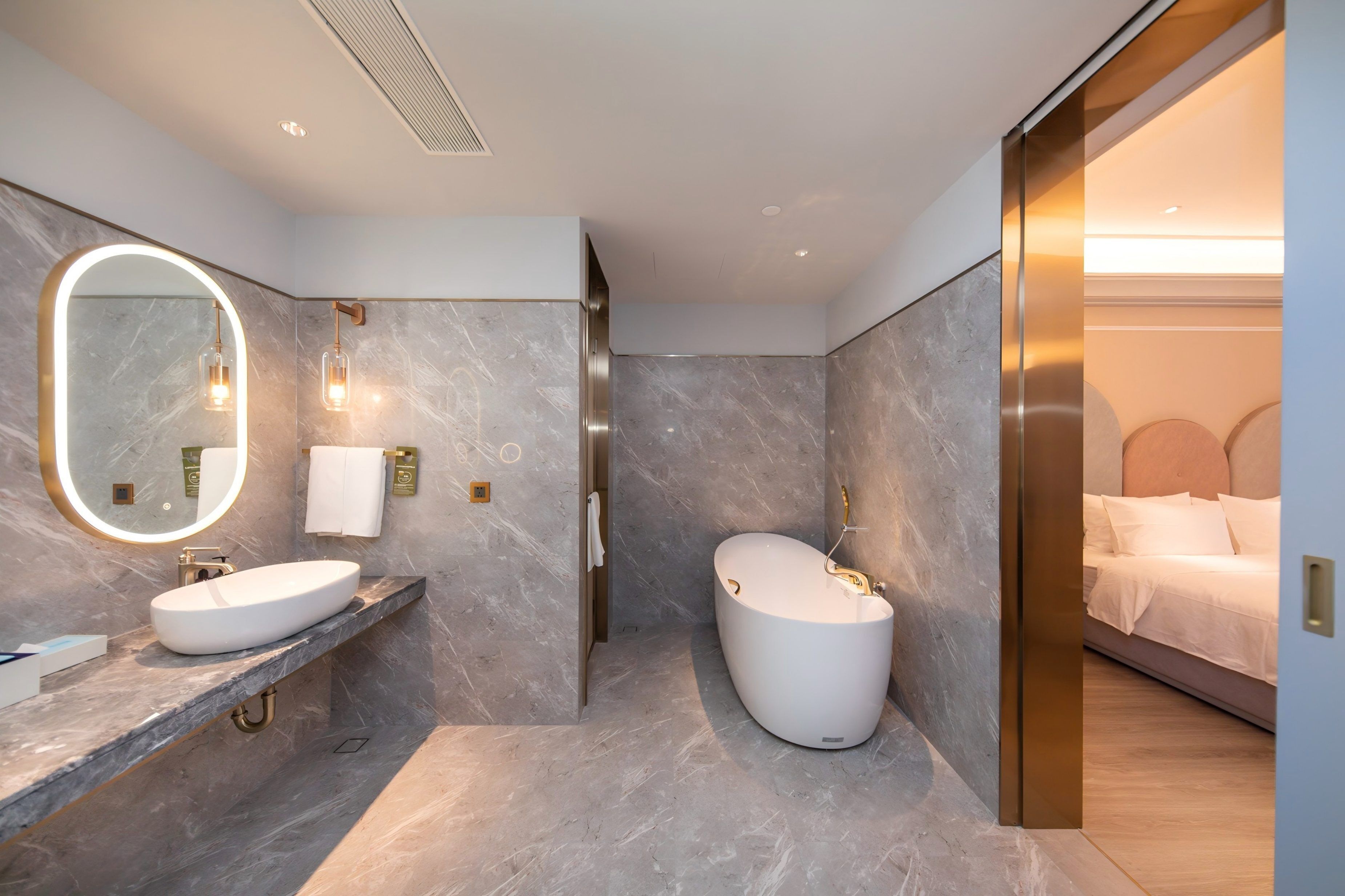 Un baño moderno con dos lavamanos, un espejo grande y una bañera independiente.