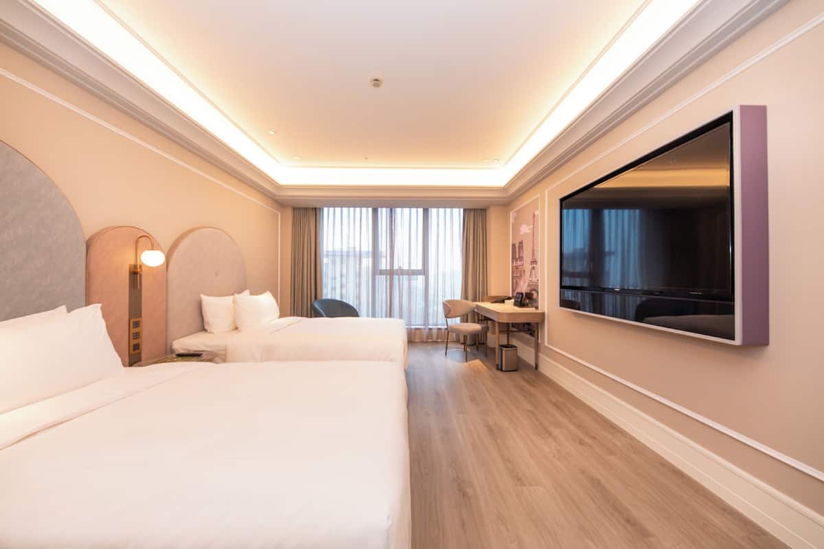 Een hotelkamer met twee bedden, een bureau, een stoel, een grote spiegel en een televisie.