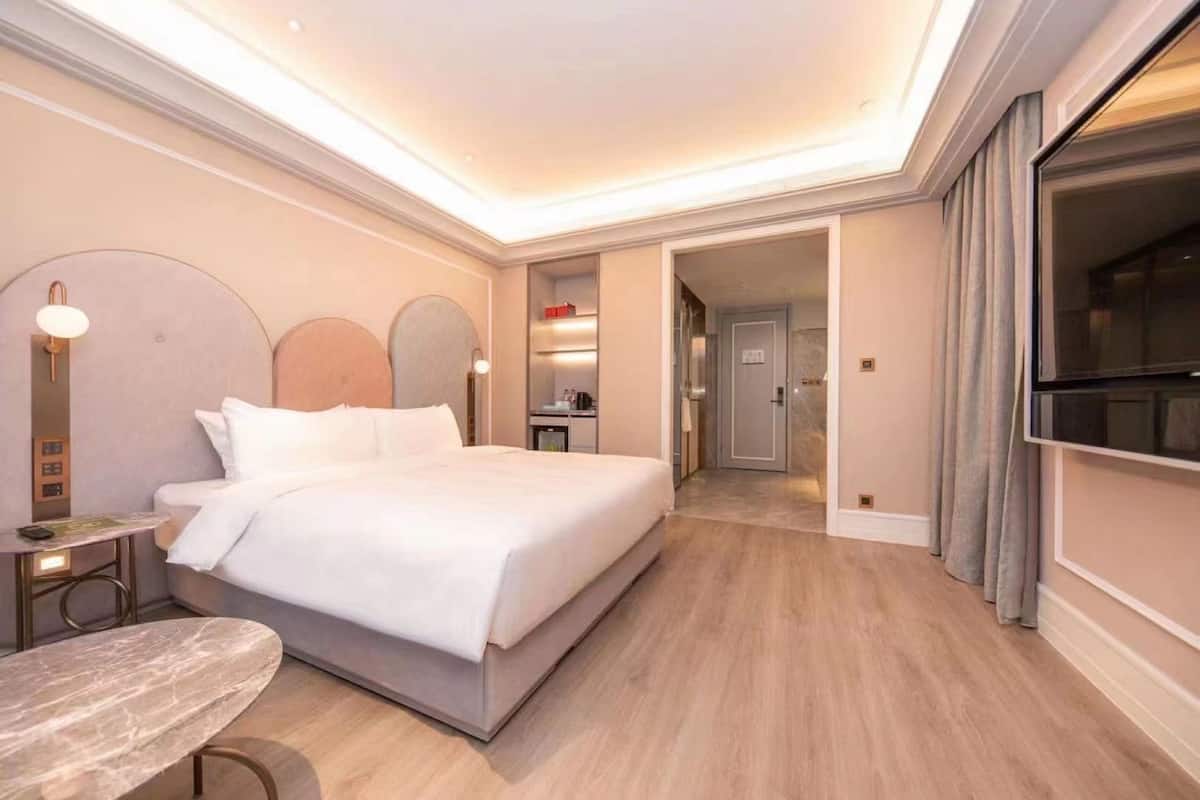 Een hotelkamer met een bed, nachtkastje en televisie.
