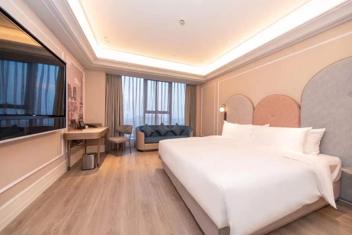 Een hotelkamer met een groot bed, een bureau, een bank en een televisie.