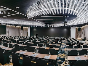 A conference room with rows of tables, chairs, and a large chandelier. - Novotel Johor Bahru City Centre (Johor Bahru)