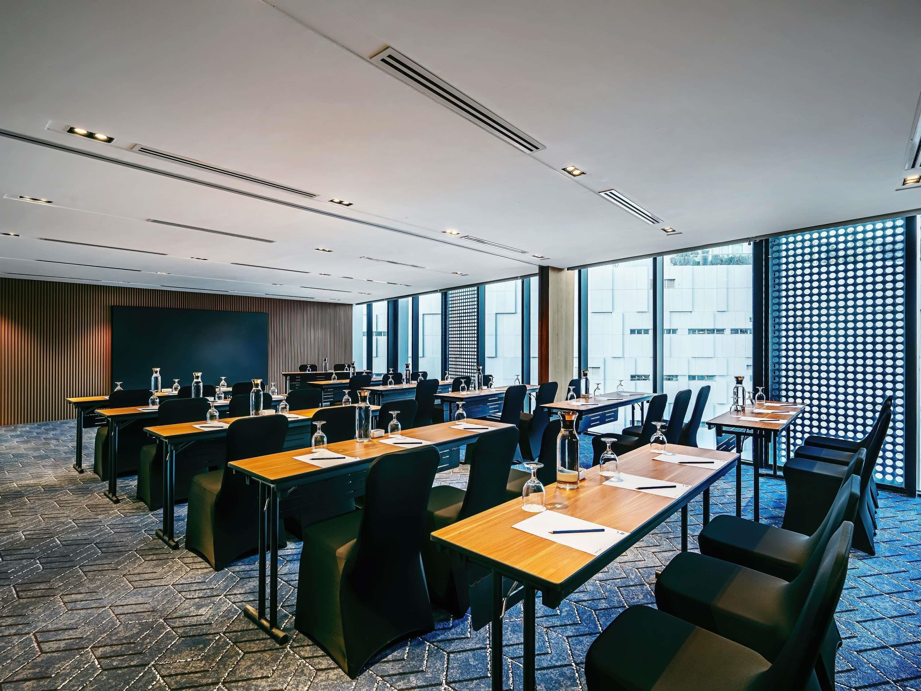 A conference room with multiple tables and chairs, large windows, and a patterned floor.