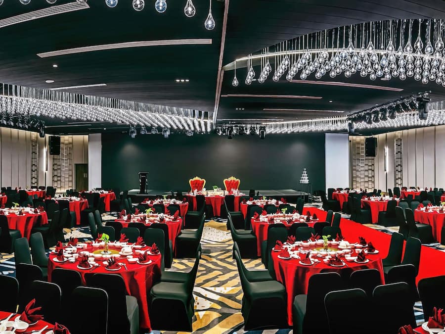 A banquet hall with rows of tables, a stage, and a chandelier.