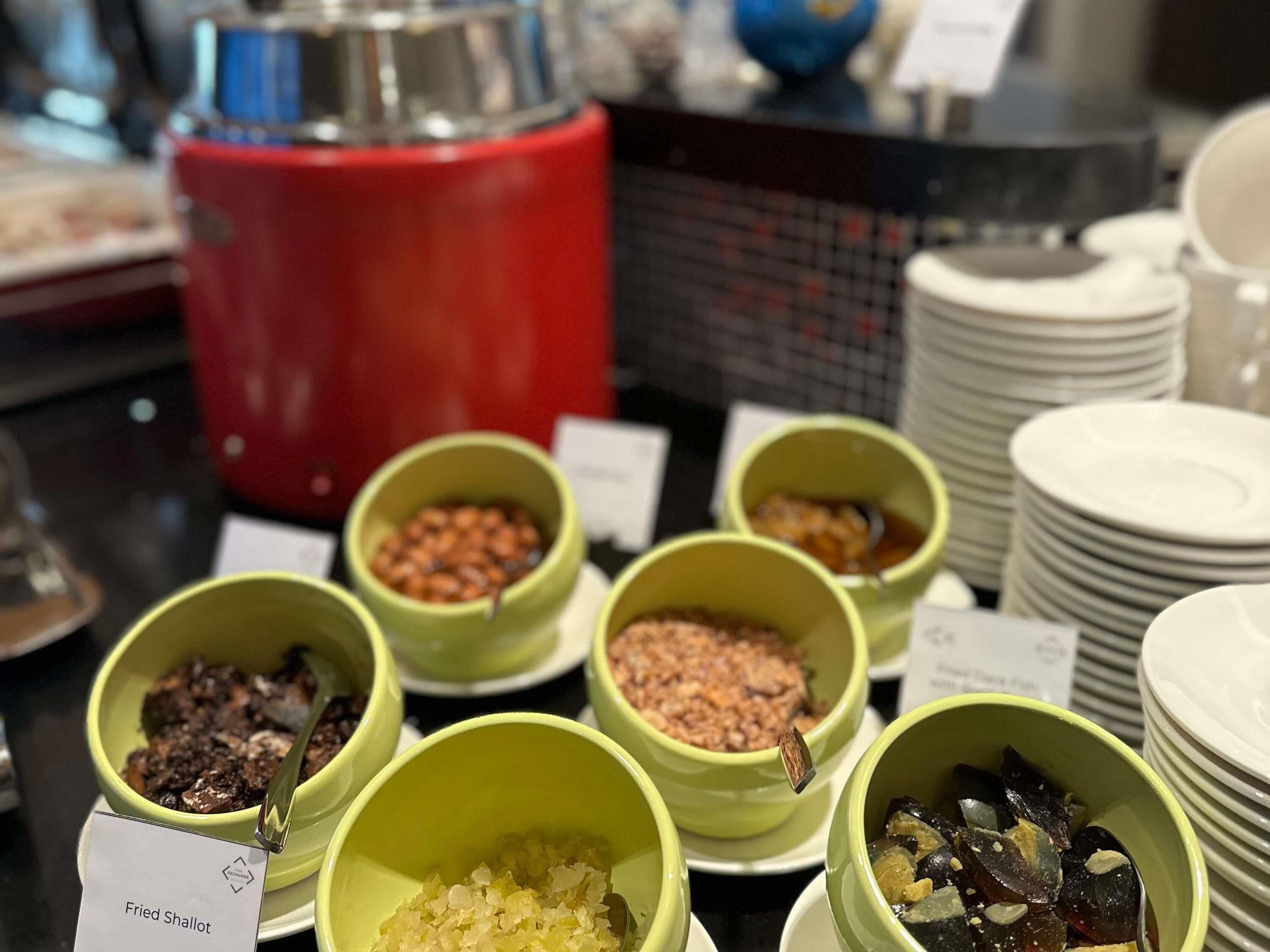 A buffet with various dishes in green bowls, including fried shallot.