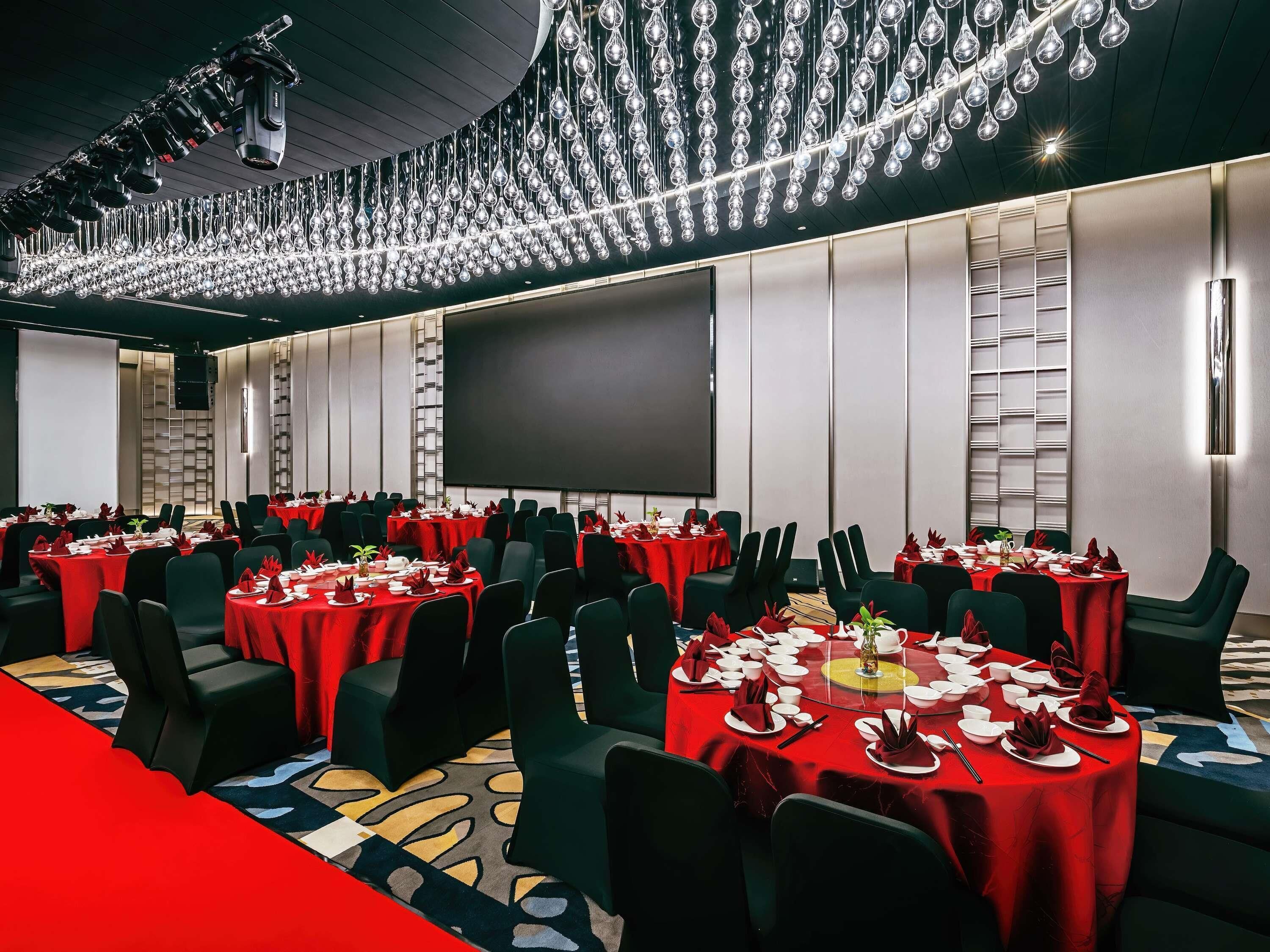 A conference room with round tables, red tablecloths, and black chairs.