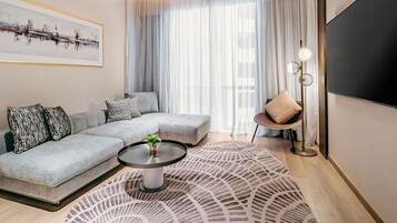 A modern living room with a sectional sofa, a coffee table, a floor lamp, and a large TV.