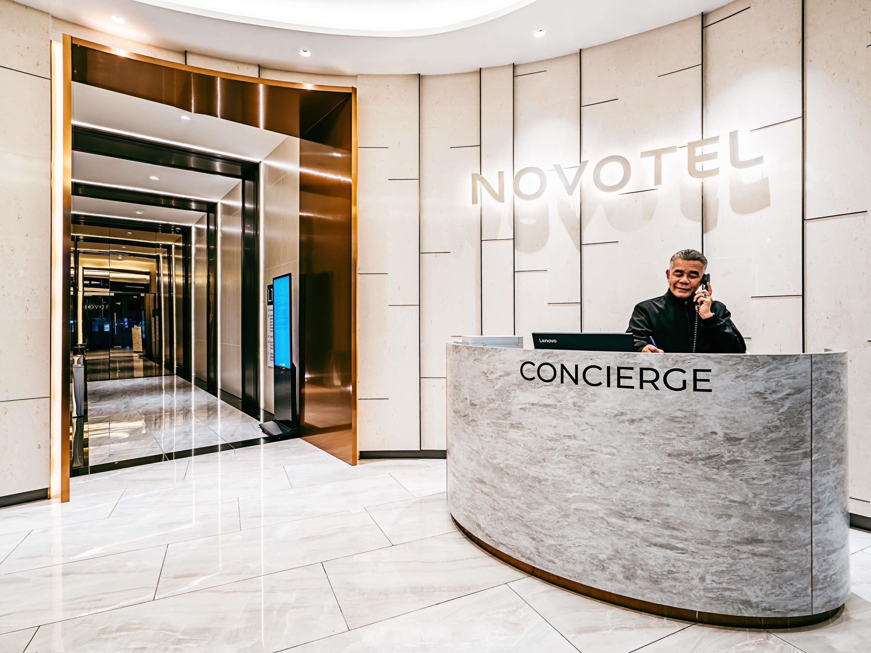 A hotel reception area with a concierge desk, a digital screen, and a modern interior design.