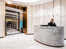 A hotel reception area with a concierge desk, a digital screen, and a modern interior design.