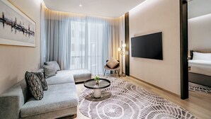 En moderne stue med en sofa, et sofabord, et fjernsyn og et mønstret tæppe.