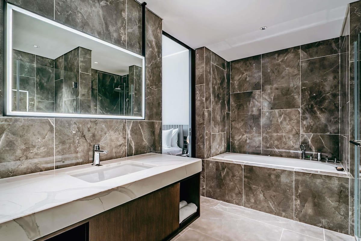 A modern bathroom with a large mirror, a sink, a bathtub, and a shower area.