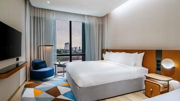 Habitación de hotel con una cama grande, televisión, escritorio y vistas de la ciudad.