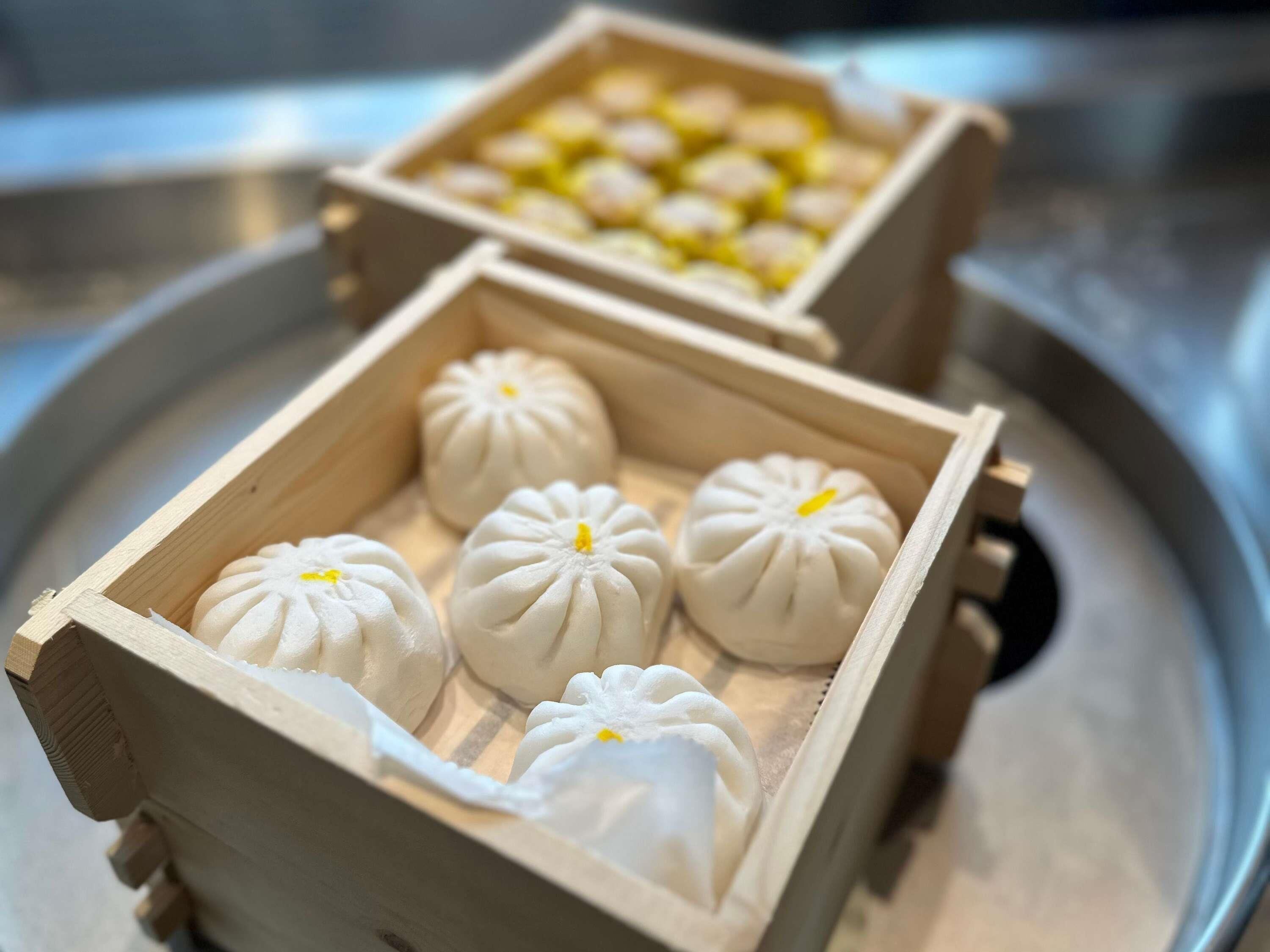 Un plateau avec deux boîtes en bois contenant des raviolis blancs.