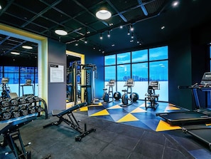 A gym with exercise equipment, treadmills, and a city view through large windows. - Novotel Johor Bahru City Centre (Johor Bahru)