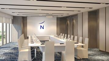 Un salón de conferencias con una larga mesa, sillas y un logotipo en la pared.