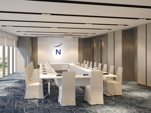 Ett konferensrum med ett långt bord, stolar och en logotyp på väggen.
