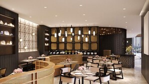 Et moderne restaurantinteriør med et buet siddeområde, flere borde og en dekorativ væg med hylder.