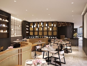 A modern restaurant interior with a curved seating area, multiple tables, and a decorative wall with shelves. - Novotel Johor Bahru City Centre (Johor Bahru)