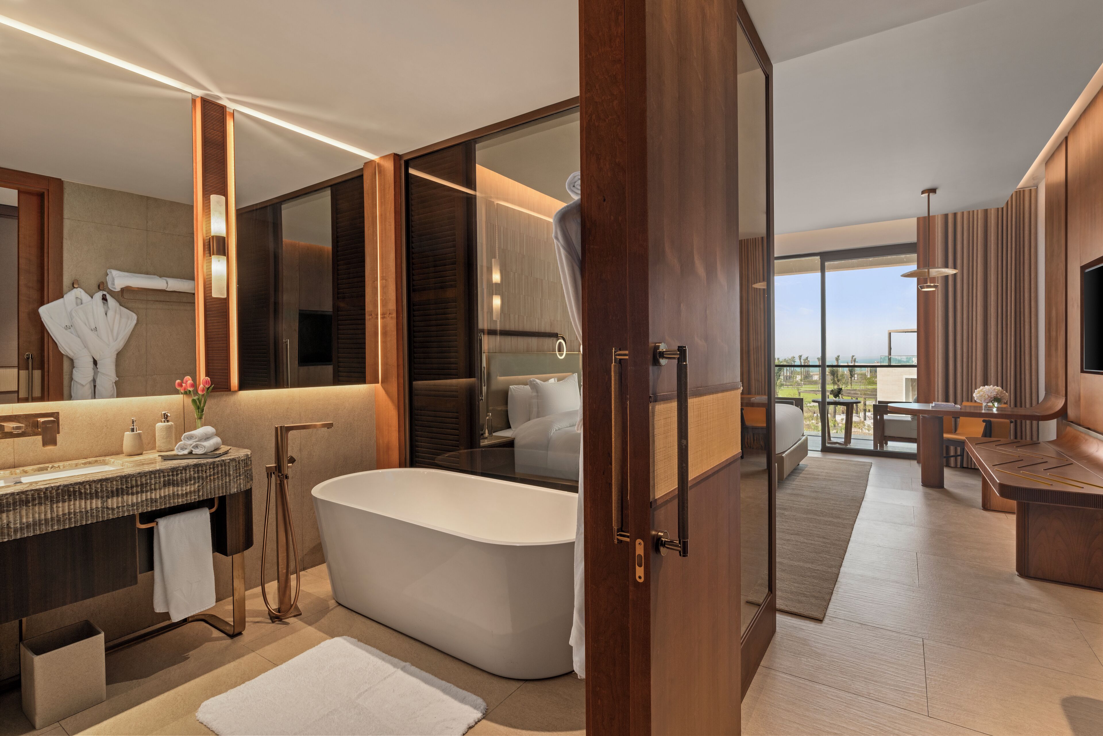 A modern bathroom with a freestanding bathtub, a vanity with a mirror, and a large window offering a view of the outdoors.