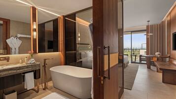 A modern bathroom with a freestanding bathtub, a vanity with a mirror, and a large window offering a view of the outdoors.