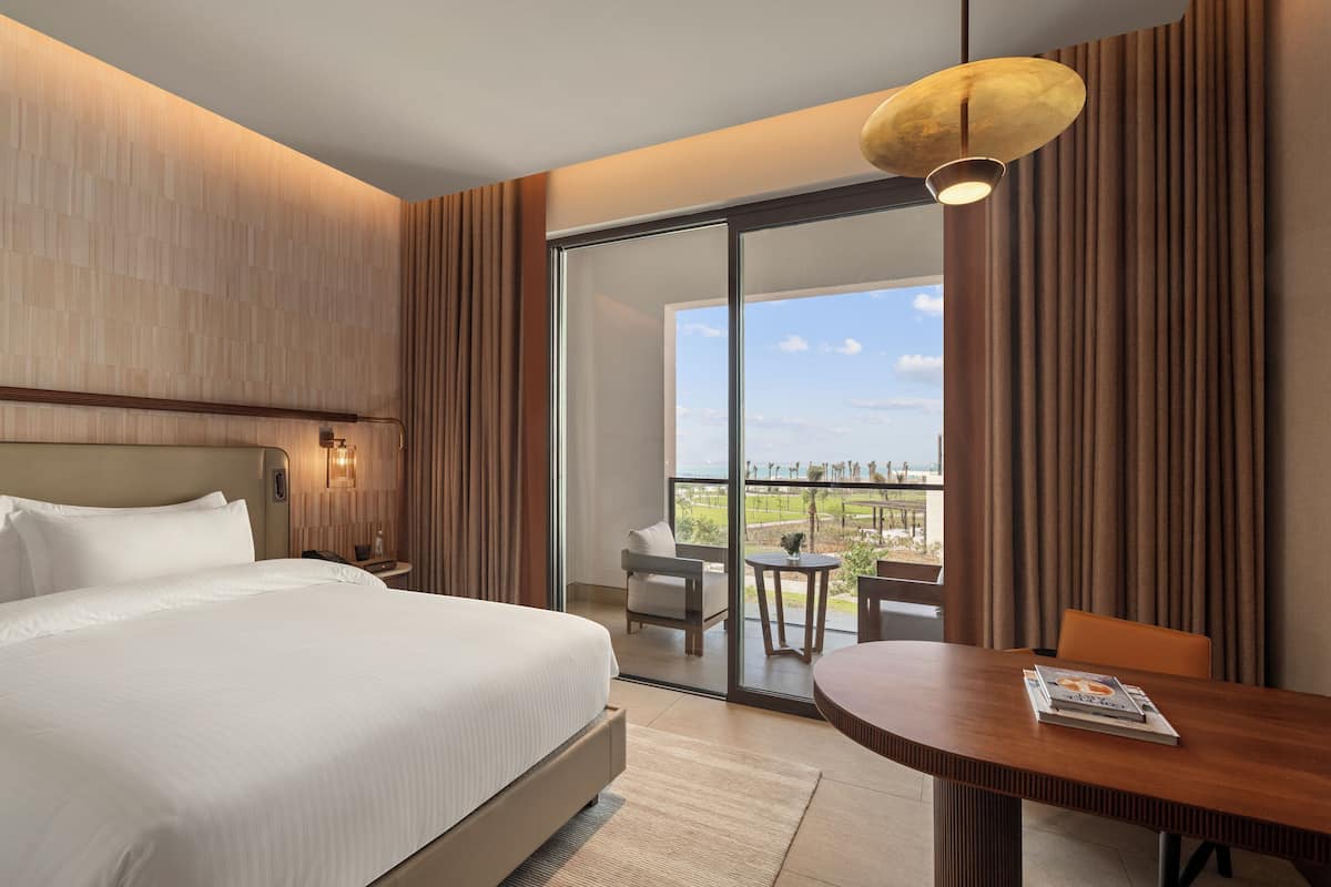 Una habitación de hotel con una cama grande, una mesa de comedor y un balcón con vistas.