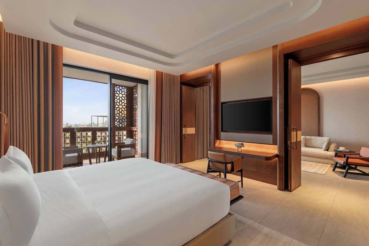 Una habitación de hotel moderna con una cama grande, un escritorio con televisor de pantalla plana, un sofá y un balcón con vistas.