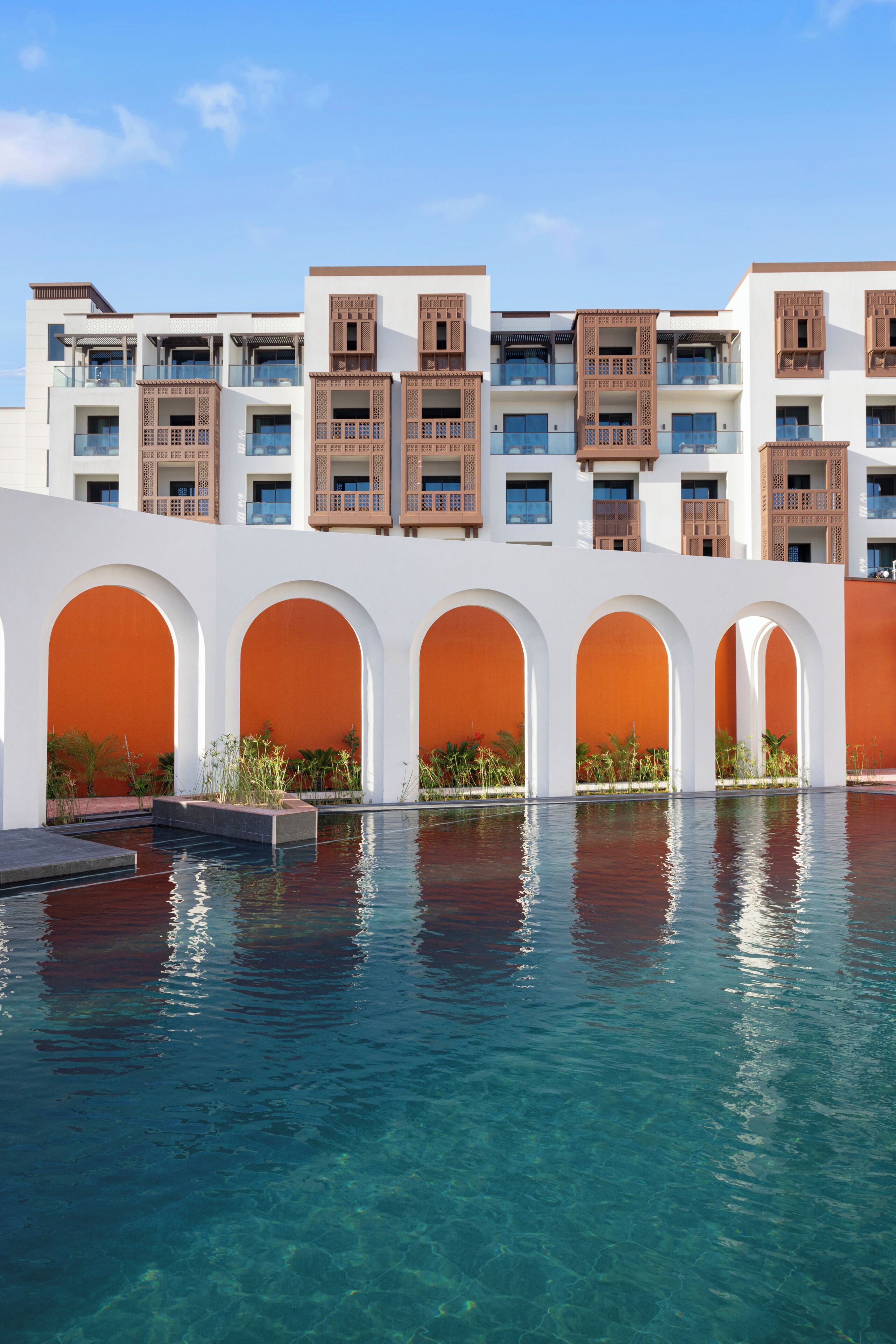 Un hôtel doté de nombreux balcons, d’une piscine et de passages voûtés.