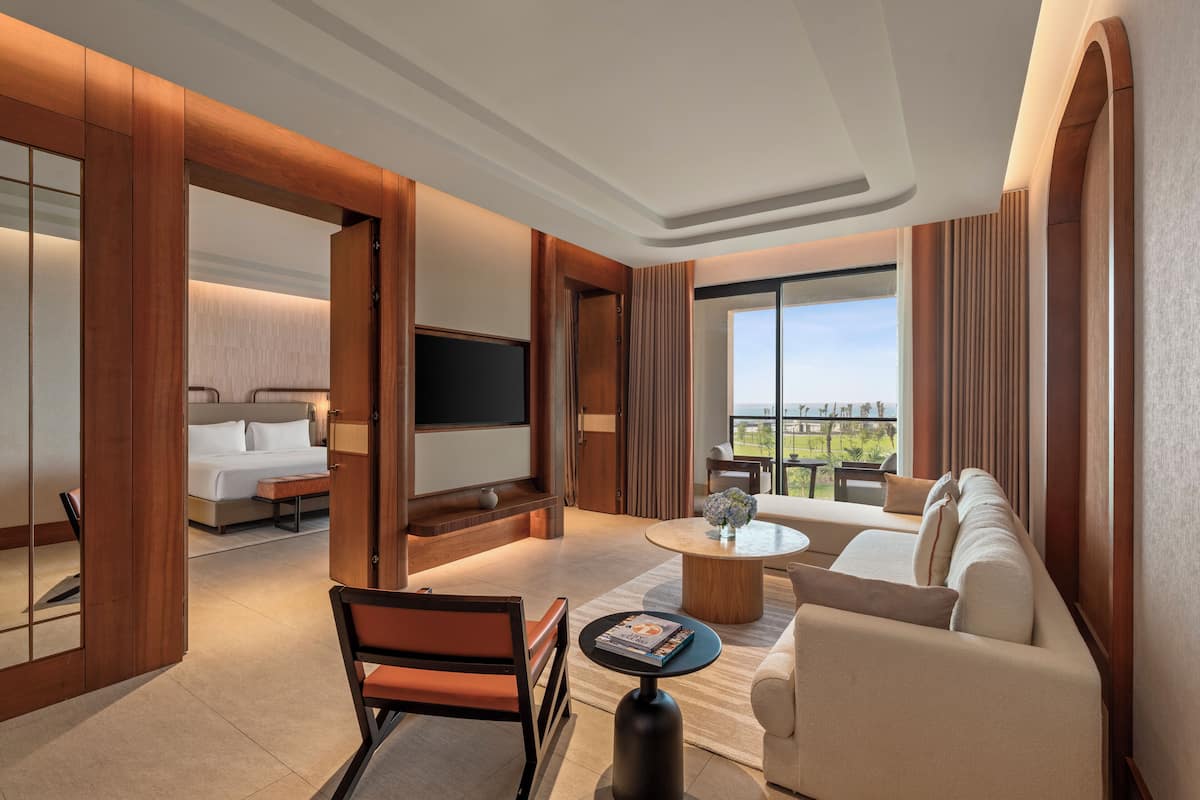Una habitación de hotel moderna con una cama grande, un sofá, una mesa de centro y un televisor.