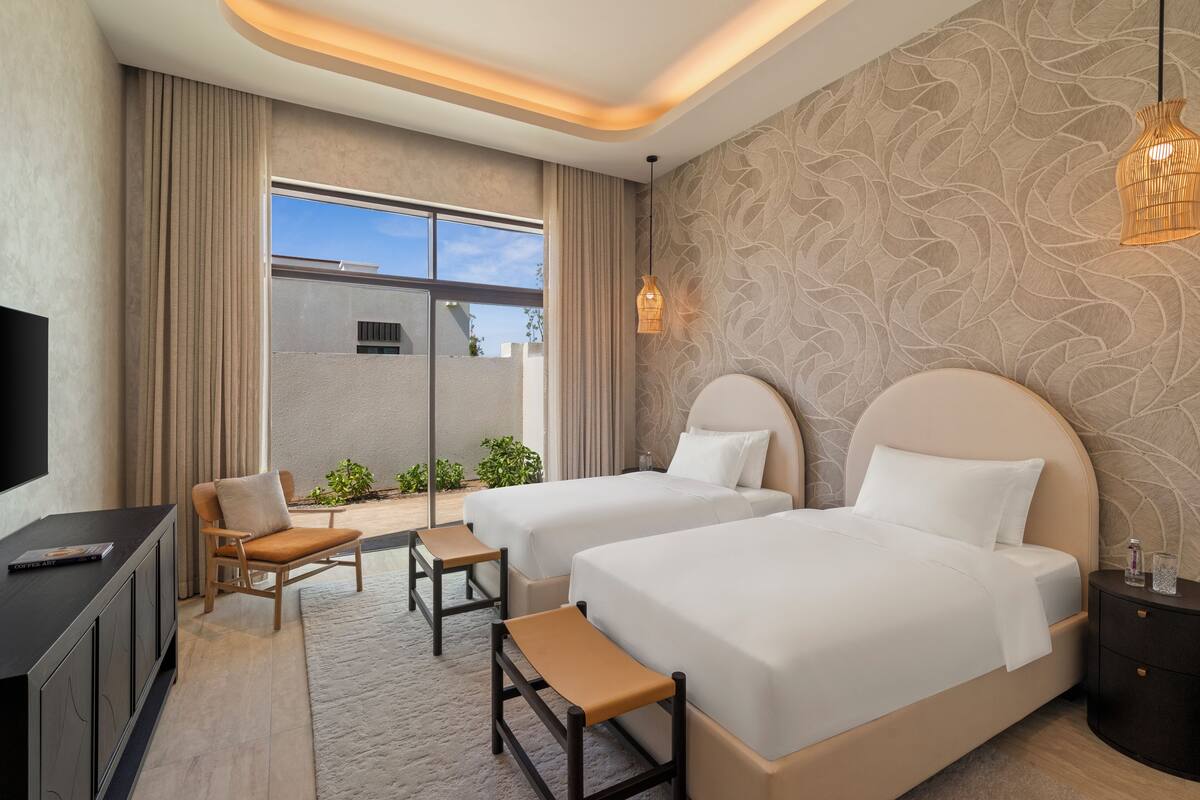Habitación de hotel con dos camas, televisión, escritorio y vistas al exterior.