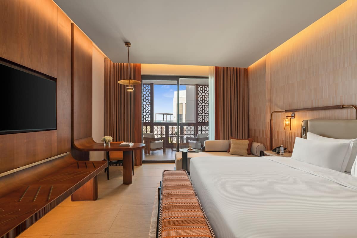 Una habitación de hotel moderna con una cama grande, un escritorio y un balcón con vistas.