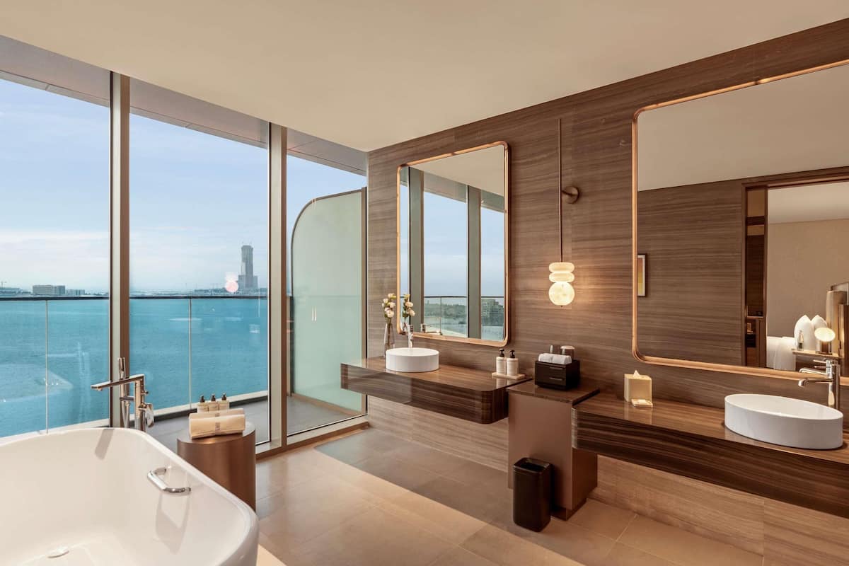 A modern bathroom with a large bathtub, two sinks, and a large mirror.