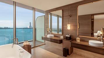 A modern bathroom with a large bathtub, two sinks, and a large mirror.