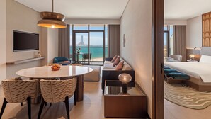 A modern hotel room with a dining area, a sofa, a bed, and a view of the sea. - So/ Ras Al Khaimah Hotel & Resort (Ras Al Khaimah)