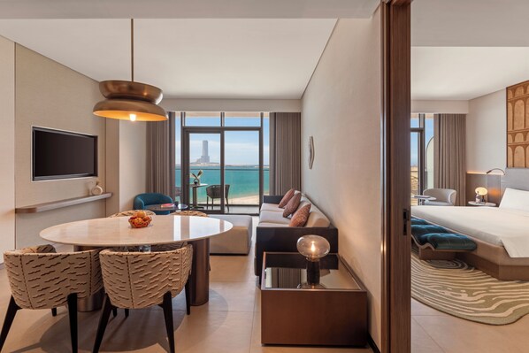 A modern hotel room with a dining area, a sofa, a bed, and a view of the sea. - So/ Ras Al Khaimah Hotel & Resort (Ras Al Khaimah)