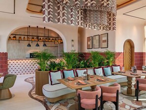 A modern dining area with a long table, cushioned seating, and hanging pendant lights. - So/ Ras Al Khaimah Hotel & Resort (Ras Al Khaimah)