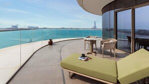 A balcony with a view of the sea, a lounge chair, a table, and a potted plant. - So/ Ras Al Khaimah Hotel & Resort (Ras Al Khaimah)