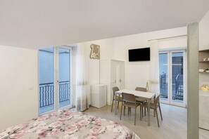 A bedroom with a bed, a desk, and a chair, a balcony, and a TV mounted on the wall. - Apartment 'Casa Imperati' with Mountain View, Wi-Fi and Air Conditioning (Agerola)