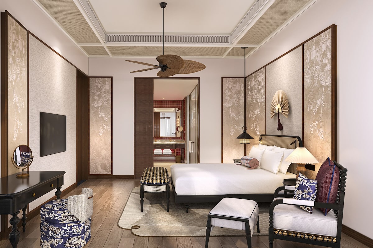 Une chambre d’hôtel équipée d’un lit, d’une table de chevet, d’une chaise et d’un ventilateur de plafond.