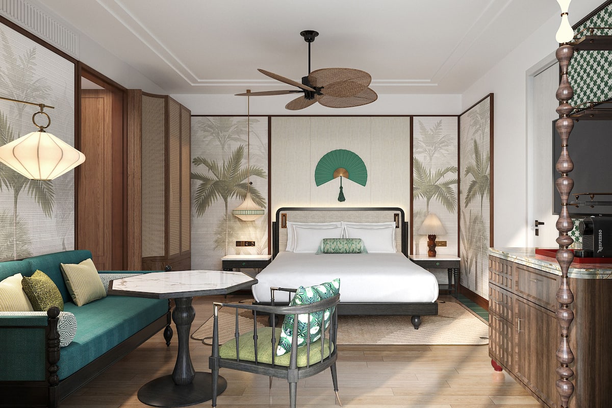 Une chambre d’hôtel comprenant un lit, un canapé, une chaise, un ventilateur de plafond, une lampe fixée au mur et une machine à café.