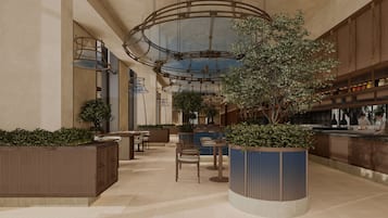 Um espaço amplo e coberto, com assentos, um elemento de decoração com plantas no centro e um bar.