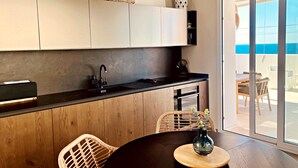 Eine moderne Küche mit Holzausstattung, einer schwarzen Arbeitsplatte und einem Essbereich mit Korbstühlen.