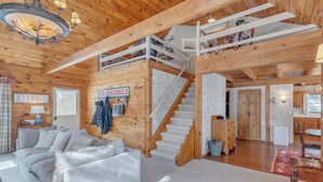 Ein Holzblockhaus-Innenraum mit Treppe, einer Couch und einem Schild mit der Aufschrift 'Erdbeeren'.