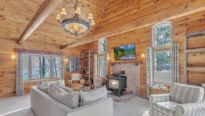 Ein gemütliches Blockhaus-Interieur mit Kamin, bequemen Sitzgelegenheiten und einem Fernseher.