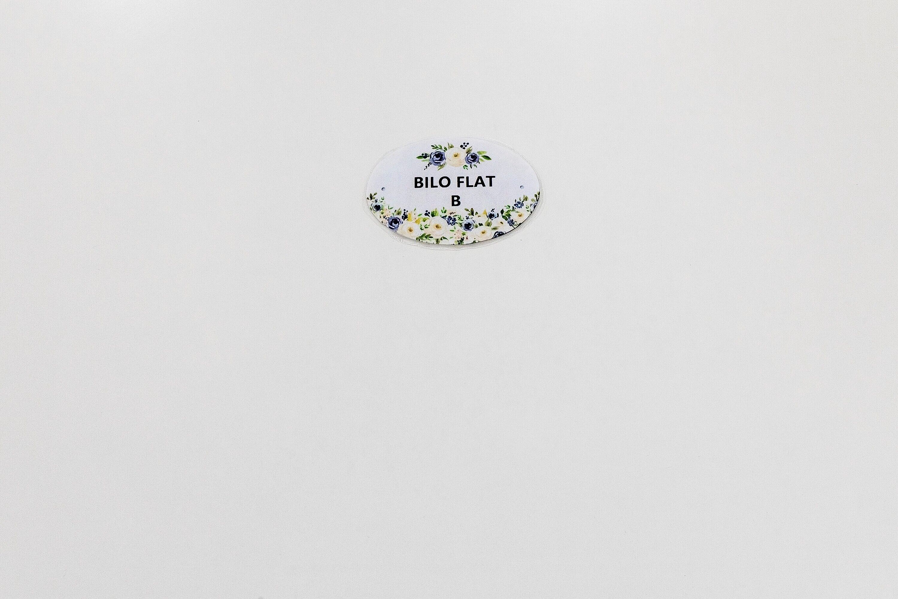 A circular object with floral patterns and text 'BILO FLAT B' on a plain background.