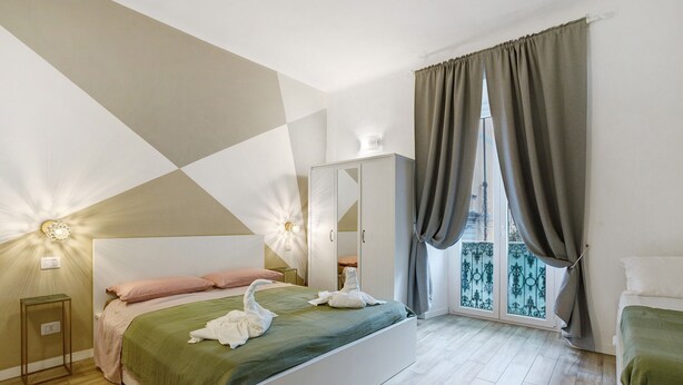 A bedroom with a bed, a wardrobe, a nightstand, and a window with curtains. - Apartment 'Mono' with Wi-Fi and Air Conditioning (La Spezia)